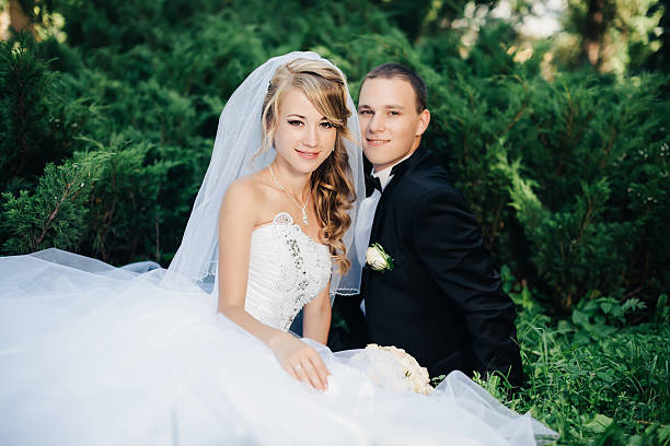istock Bride sit together with groom on green grass park 512223144