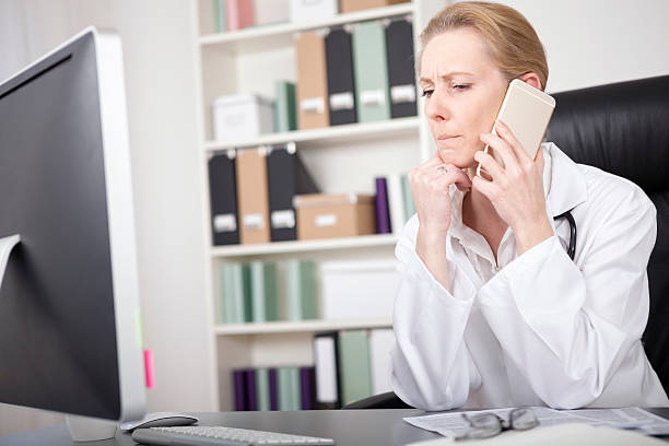 woman doctor listening to someone over the phone - nurse on phone serious bildbanksfoton och bilder