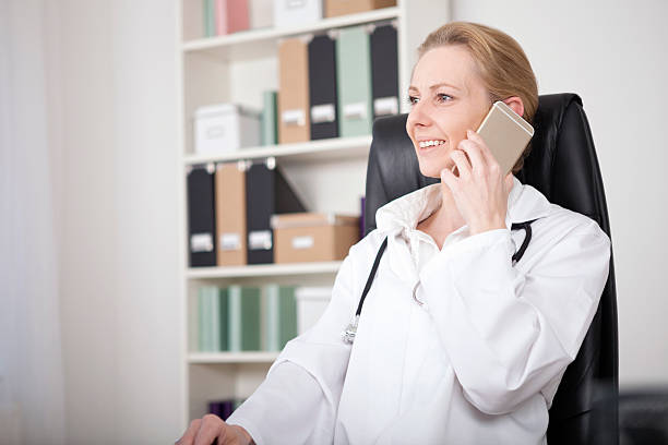 smiling female doctor calling on mobile phone - nurse on phone serious bildbanksfoton och bilder