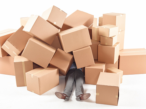 Man lying on the floor covered with boxes.
