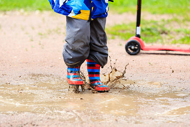istock child playing in water puddle, kids outdoor 512228030