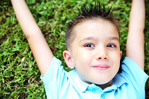 istock Portrait of a little boy lying on the grass 512248631