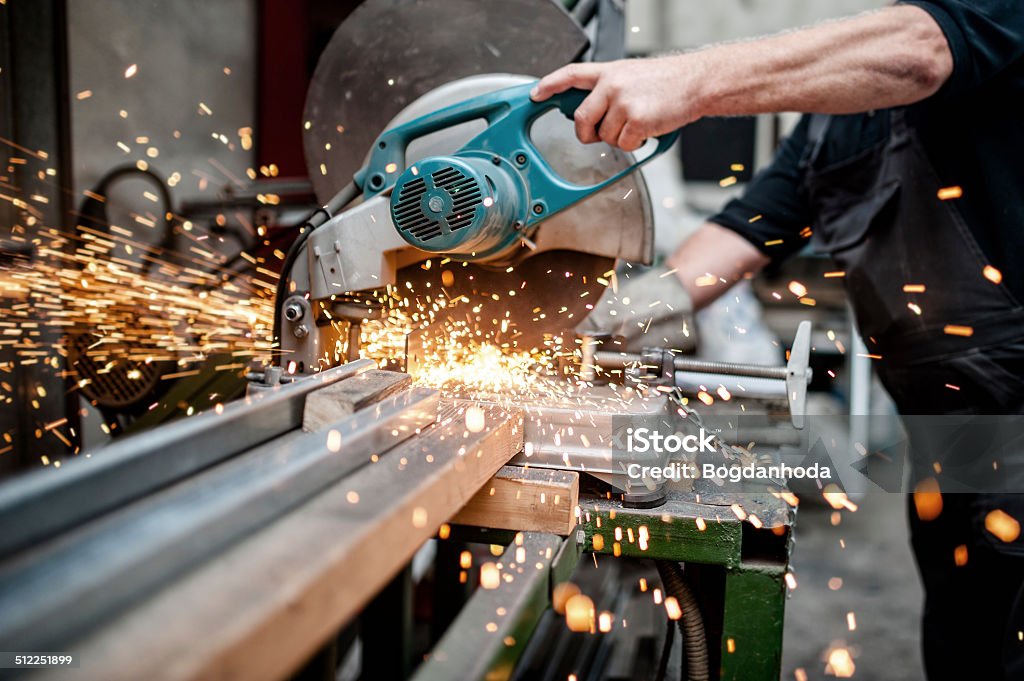 man, worker using a sliding compound mitre saw man, worker using a sliding compound mitre saw with circular blade for cutting meta Metal Stock Photo