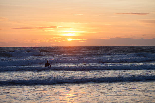 surfer am meeresstrand bei sonnenuntergang - devon north devon sunset multi colored stock-fotos und bilder