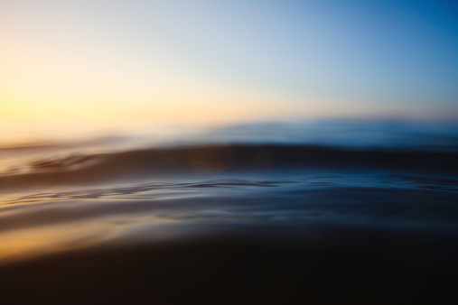A depth of field shot of the oceans surface lit up on sunrise with golds and blues.