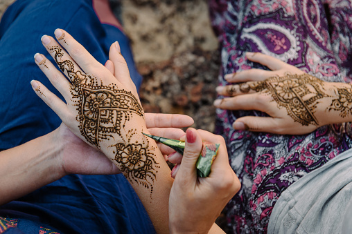 Applying henna tattoo on women hands. Mehndi is traditional Indian decorative art. Close-up, top view