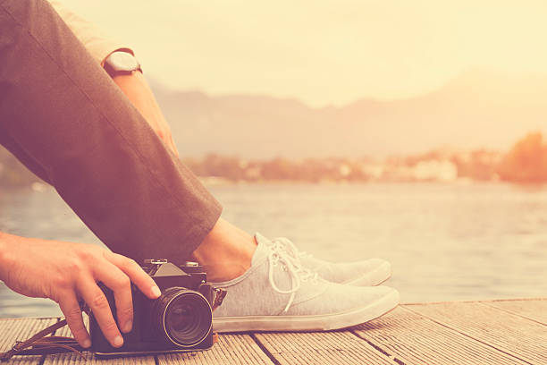 Hipster man taking photos with camera on the river.