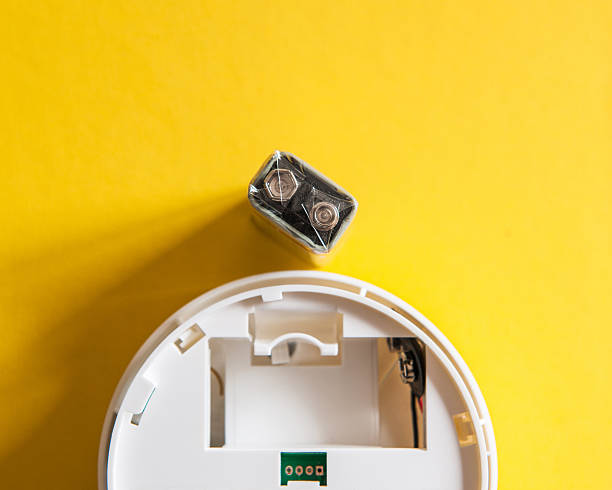 White smoke detector with nine volt battery White smoke detector with nine volt battery on yellow background. A smoke detector is a device that senses smoke, typically as an indicator of fire. smoke detector photos stock pictures, royalty-free photos & images