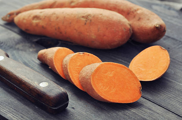 Raw sweet potatoes Raw sweet potatoes on wooden background closeup sweet potato photos stock pictures, royalty-free photos & images