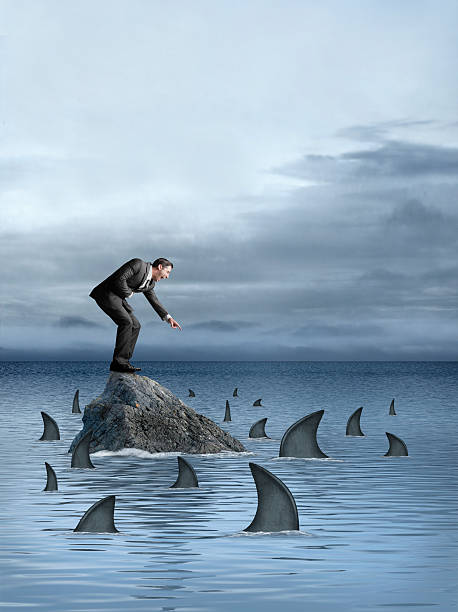 istock Businessman laughing and pointing at sharks that surround him 512278467