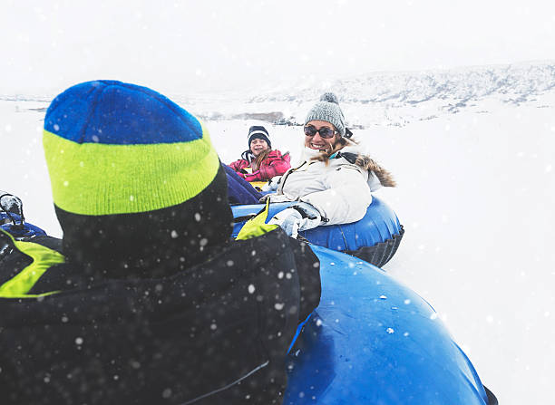 istock Family sledding down a hill on inflatable snow tubes 512280560