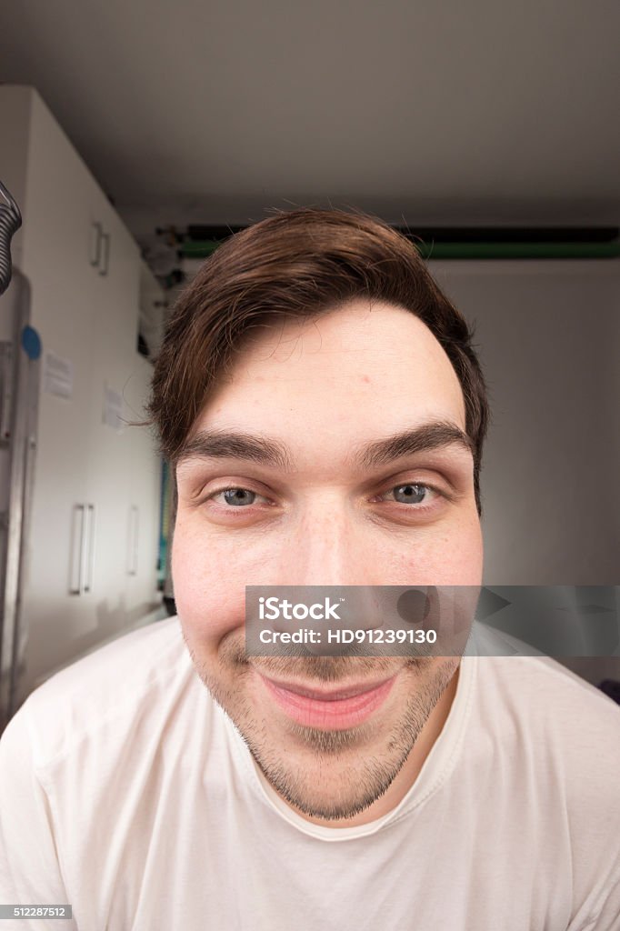 Face close up portrait of pronounced wide angle shot. Face close up portrait of young caucasian male man, emphasised wide angle shot. Various funny expressions. Shallow depth of field. Distorted Stock Photo