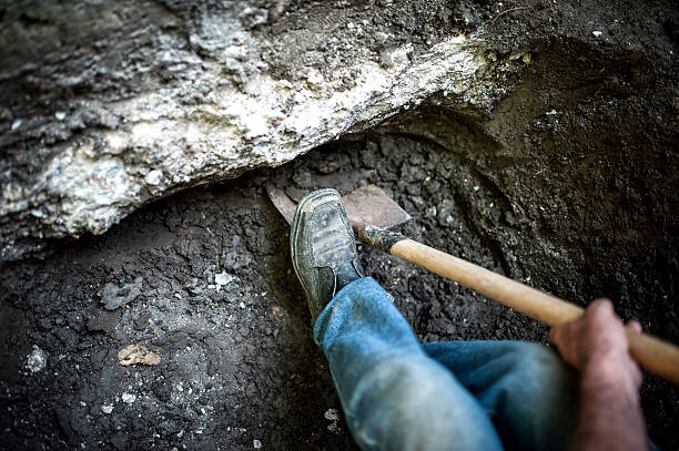istock man with shovel working at a hole in the ground 512289459