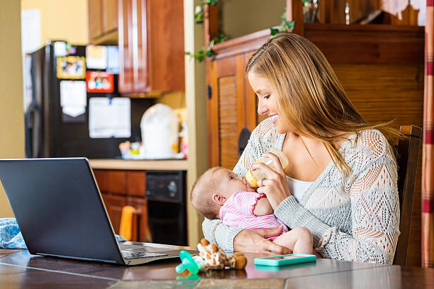 istock Mother attempting to breastfeed baby while workin gfrom home office 512290023