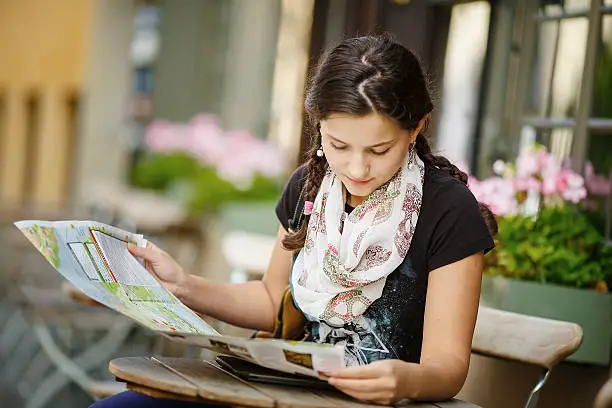 Photo of Pretty young female tourist studying a map