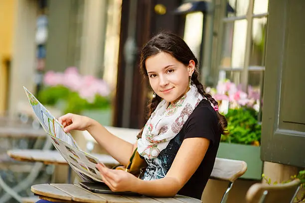 Photo of young girl sitting in a cafe studies map