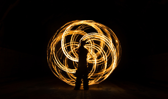 Fire juggler draws symmetric flower of life shape with fire staff. Photo exposed 10 seconds to bring out the symmetric shape perfectly.
