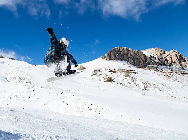 Snowboarder is jumping from ramp.