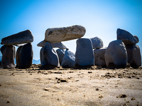 A mock stone circle made of pebbles discovered on a sunny beach at Dinas Dinlle in North Wales, UK.