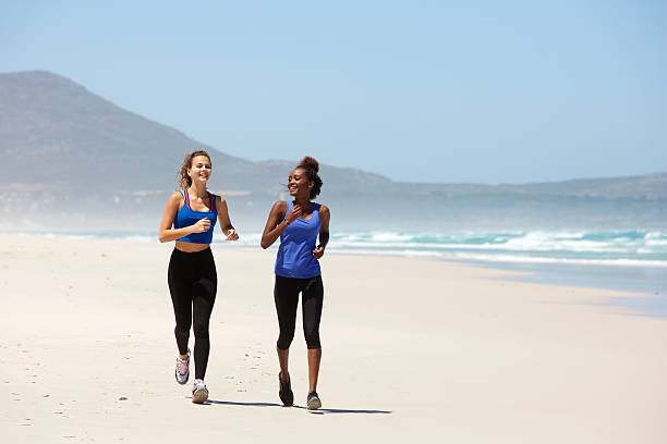 istock Two happy young women jogging on the beach 512297826
