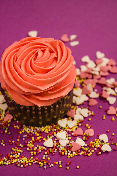 istock Cupcake with pink cream and sprinkles with purple background 512298914