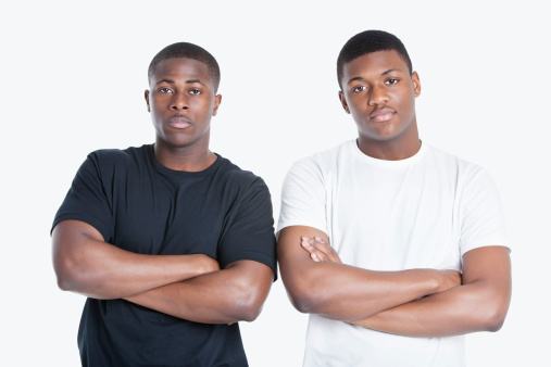 Portrait of two African American male friends with arms crossed over gray background