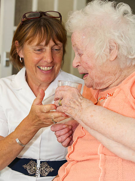 istock Female nurse carer providing a drink to a client 512311841