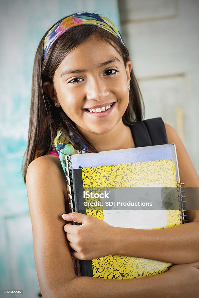 Cute Hispanic student holding books before school starts 12-13 Years Stock Photo