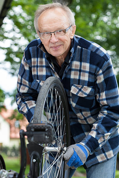 istock Smiling senior man repairing a bicycle 512321953