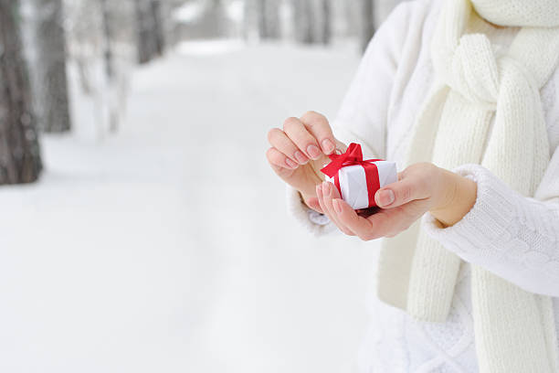 istock Woman holding a gift and begins to open it. 512328188