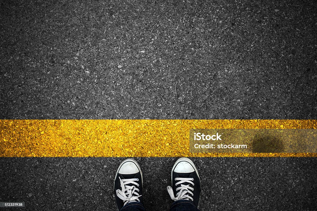 Personas en una línea amarilla inicial de asfalto - Foto de stock de Línea de salida libre de derechos
