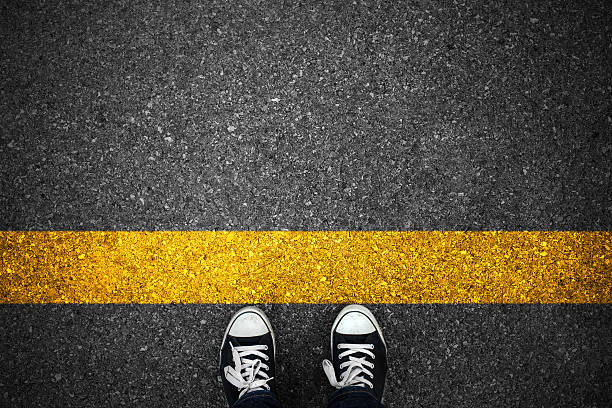 People at a starting yellow line on asphalt.
