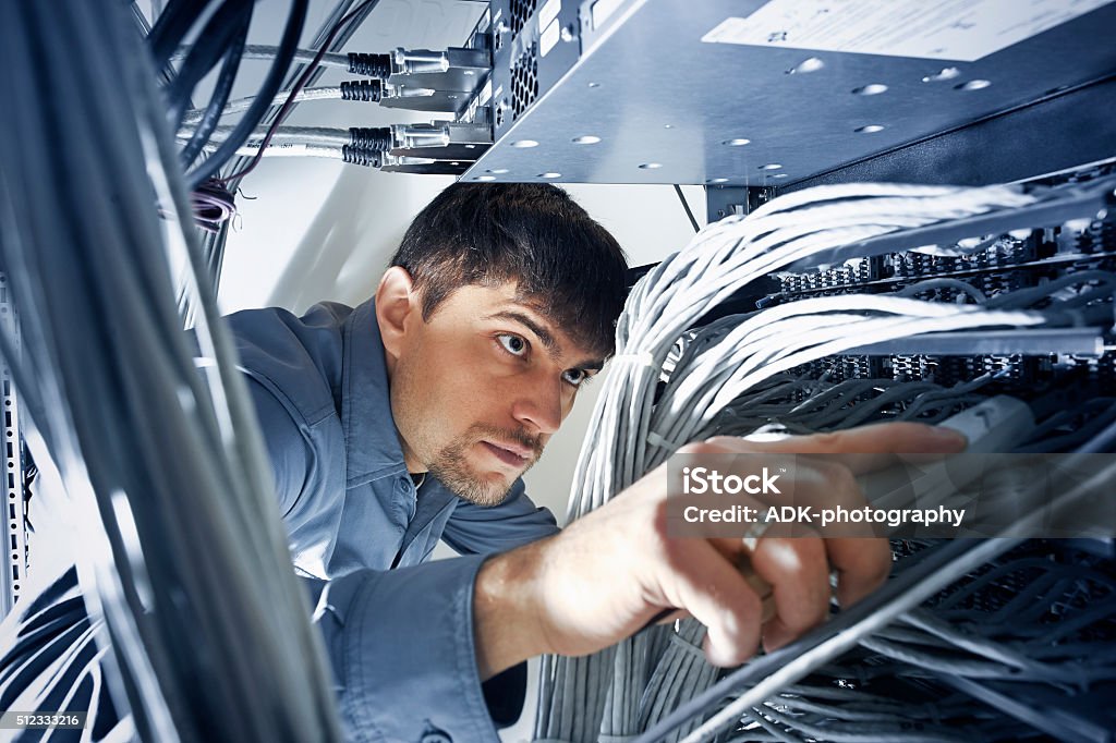 Technician engeneer is checking server's wires in data center Technician engeneer (30-35) is checking server's wires in data center Technology Stock Photo