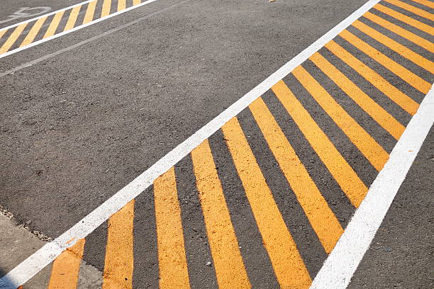 nero asfalto suolo dipinto con bande gialle - safety yellow road striped foto e immagini stock