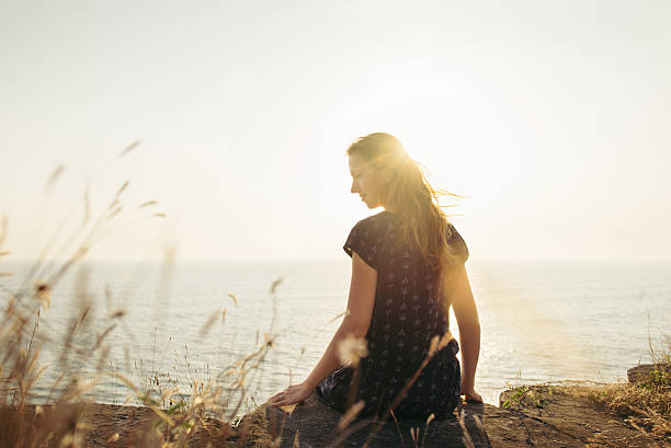 istock Happy woman sitting on the cliff on sunset background 512337232