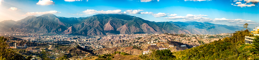Structured residential disctict vs shanty chaos in a latin america. Aerial view of architectural Chaos in poverty zones, Caracas, Venezuela.. Panoramic image of eastern Caracas city aerial view at late afternoon. Venezuela.  Showing El Avila mountain also known as El Avila National Park (Guaraira Repano).  Santiago de Leon de Caracas, is the capital city of Venezuela and center of the Greater Caracas Area. It is located in the northern part of the country, following the contours of the narrow Caracas Valley and the \