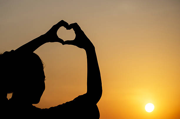 istock happiness silhouette woman making heart shape 512343338
