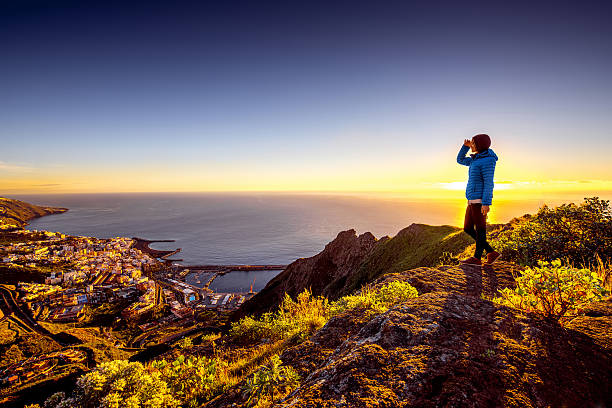 Woman enjoying landscape view near Santa Cruz city Young female traveler in blue jacket enjoying landscape view on Santa Cruz city on La Palma island in the morning la palma canary islands photos stock pictures, royalty-free photos & images