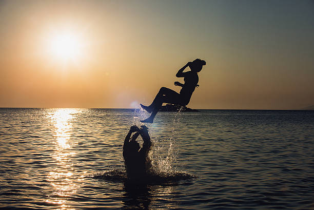 istock Two guys throwing girl from water 512345164