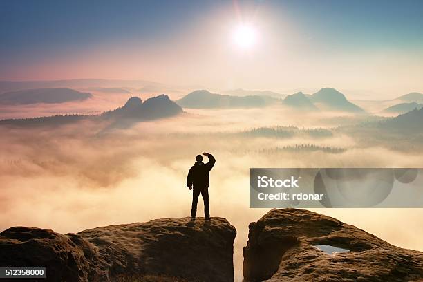 Colorful Misty Morning Tourist In Dark Cloths In Rocks Stock Photo - Download Image Now