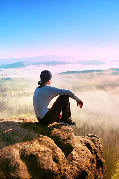 istock Sportsman in white shirt, trousars and cap on sharp cliff 512358162