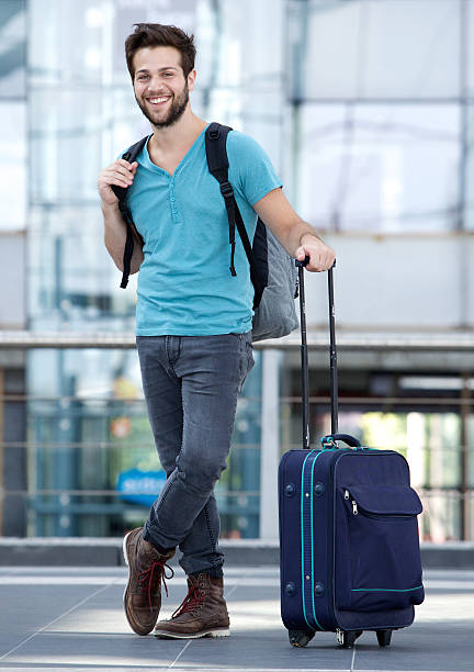 istock Young man waiting at airport with suitcase and bag 512358479