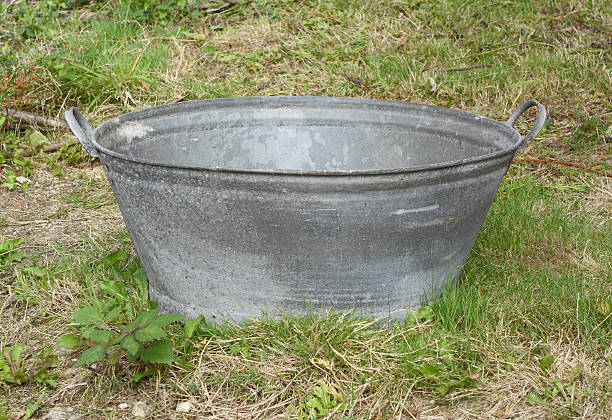 Empty tin bath Empty tin bath standing on rough grass and weeds Bucket Rain Gauge stock pictures, royalty-free photos & images