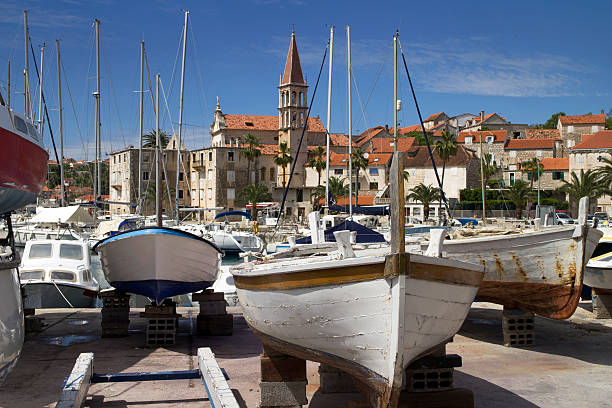 Old wooden boats and old stone houses Marina and Church in Milna, village on west side of island Brac in Croatia old catholic church on island brac croatia stock pictures, royalty-free photos & images