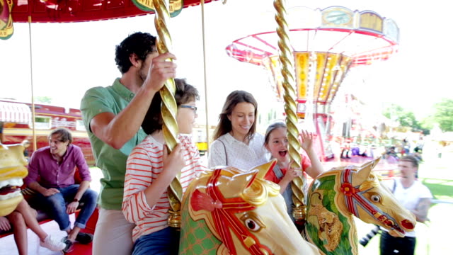 Family riding carousel in amusement park