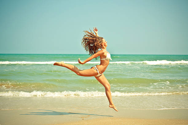 istock woman jumping on the beach 512386491