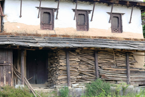 Traditional white and brown painted-stone walled-firewood crowded porch gurung townhome. Ghandruk village on the Annapurnas Tour trekking route through the foothills of the Himalayas-Kaski district-Gandaki zone-Nepal.