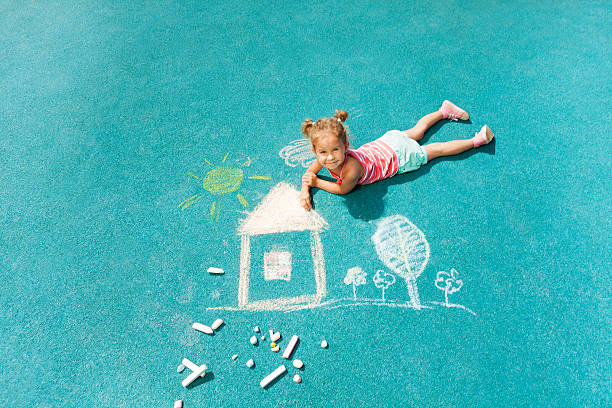 Portrait of an adorable little girl with big spectacles solving a math problem on a chalkboard at home