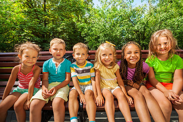 istock Row of children on the bench in park 512392487
