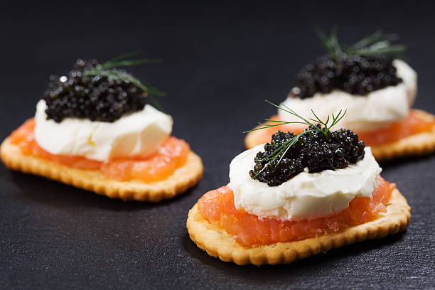 istock Black caviar served on crackers with salmon and cream cheese. 512399448
